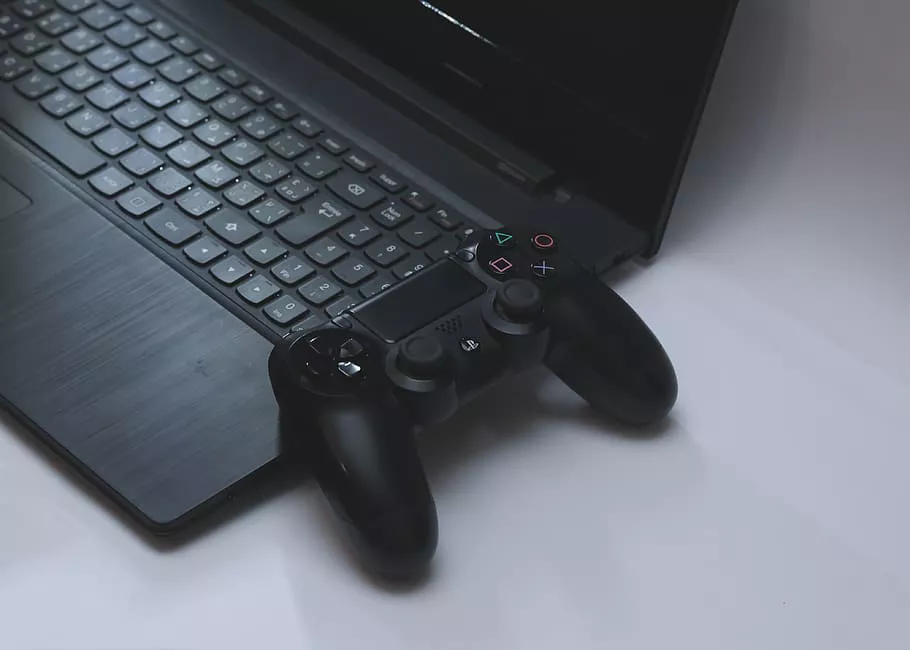 Worlds in Characters Podcast Header - A PS4 controller leaning against an open grey laptop